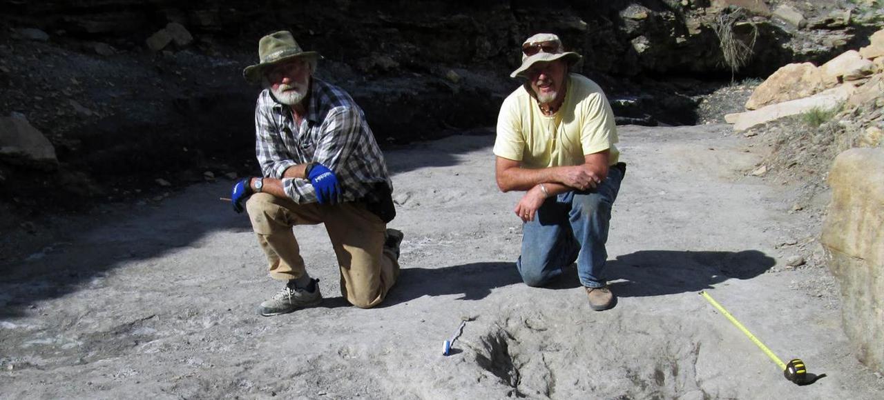 Martin Lockley et son collègue Ken Cart devant des trous creusés par des théropodes du Crétacé. (c) M.LOCKLEY / NATURE / AFP